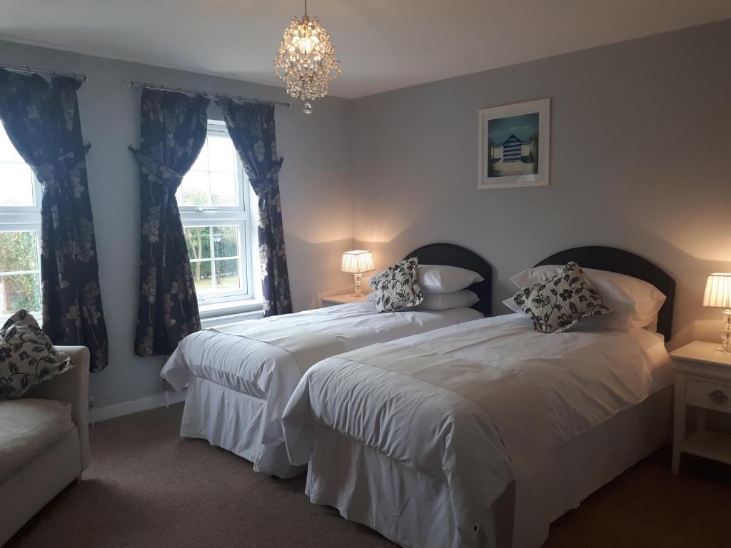 a bedroom with two beds and a chandelier at Berry House Bed & Breakfast in Littlehampton