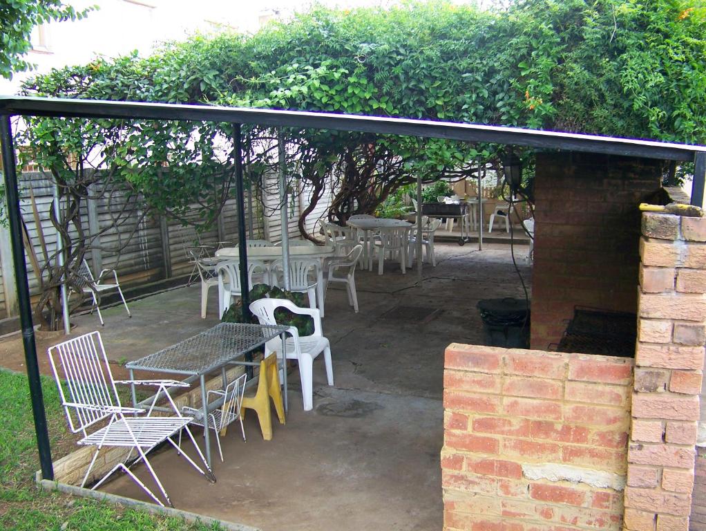 a patio with tables and chairs under an umbrella at Strelitzia Guest House in Bela-Bela