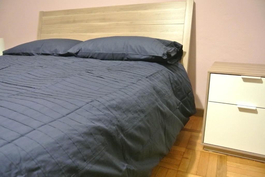 - un lit avec une couette bleue et une table de chevet dans l'établissement R&B Errepì Piola, à Milan