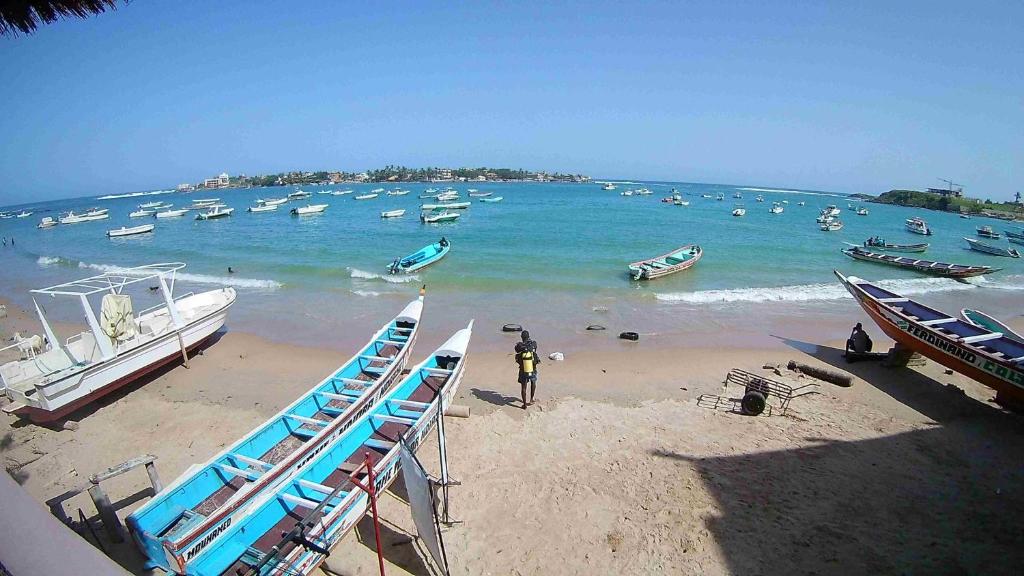 a beach with boats and people in the water at La Maison Abaka in Dakar