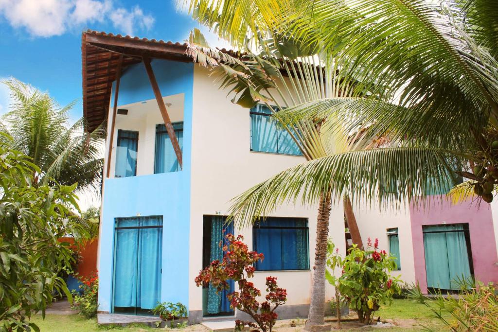 a house with blue windows and palm trees at Condominio Sao Cristovao in Santa Cruz Cabrália