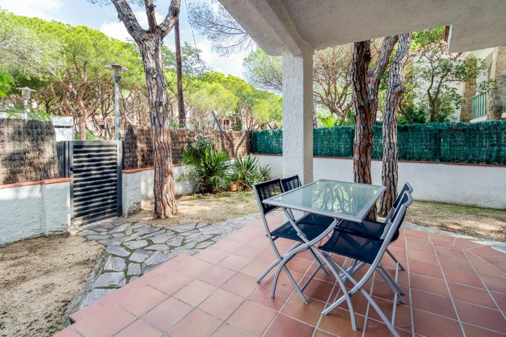 a patio with a glass table and two chairs at Hauzify I Apartament Edelweiss in Platja d'Aro
