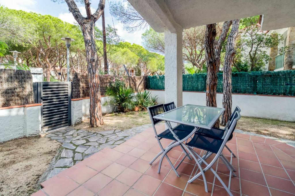 a patio with a glass table and two chairs at Hauzify I Apartament Edelweiss in Platja  d'Aro