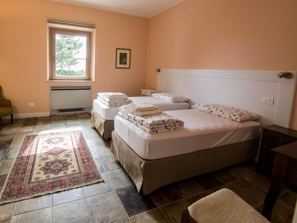three beds in a room with a rug and a window at Podere684 in Grosseto