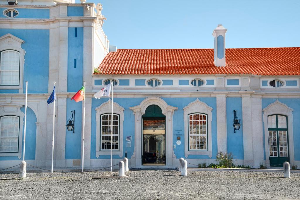 un edificio azul con dos banderas delante en Pousada Palacio de Queluz, en Queluz