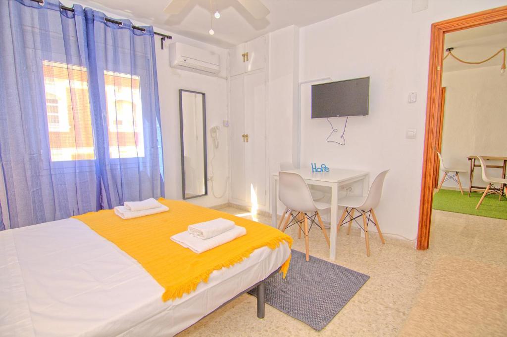 1 dormitorio con cama, mesa y TV en Low cost rooms Malaga river, en Málaga