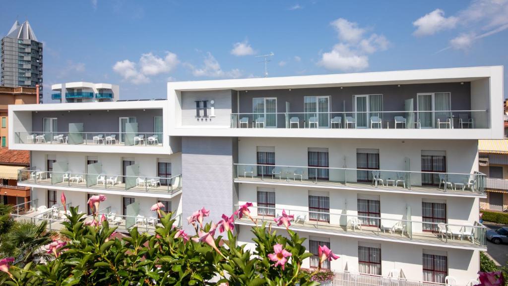an apartment building with pink flowers in front of it at Hotel Imperia in Lido di Jesolo