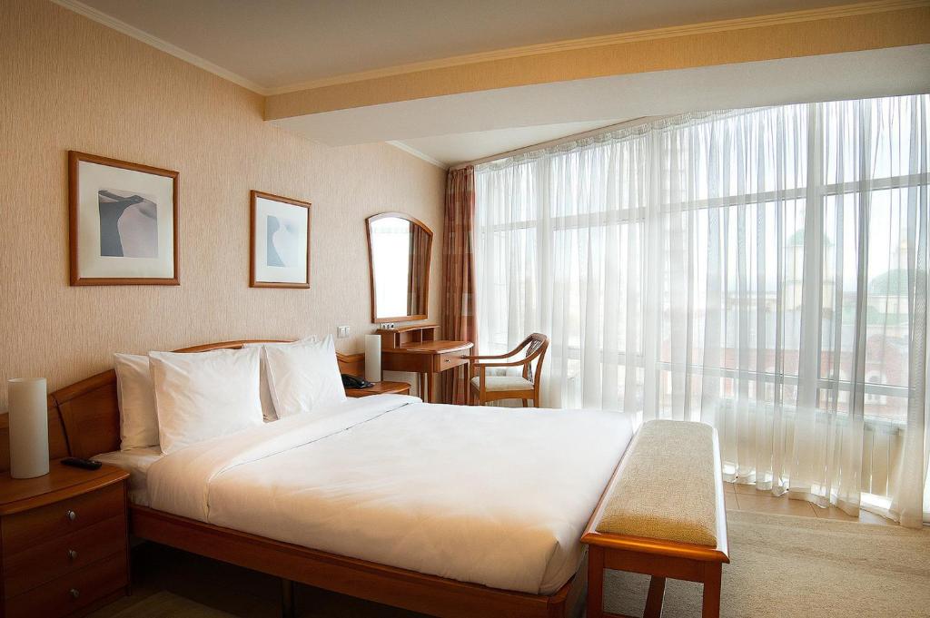 a bedroom with a large bed and a large window at Apri Hotel Perm in Perm