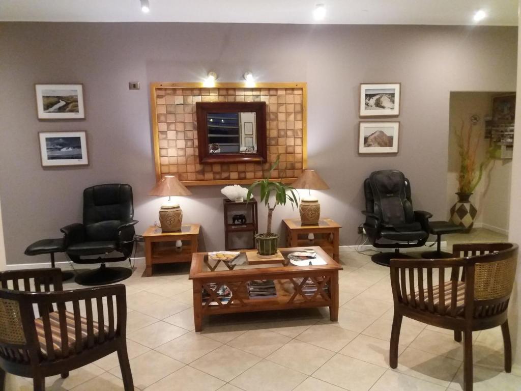 a living room with chairs and a table and a mirror at Ayelen Apart Hotel in Calama