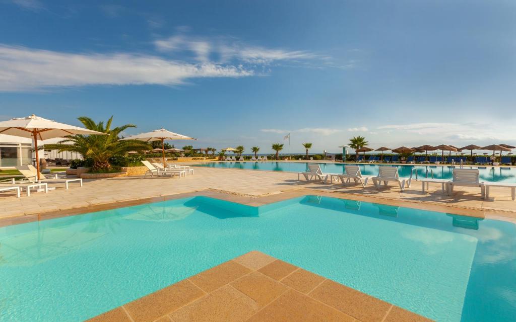a swimming pool with chairs and umbrellas at a resort at Hotel Nour Congress & Resort in Bizerte