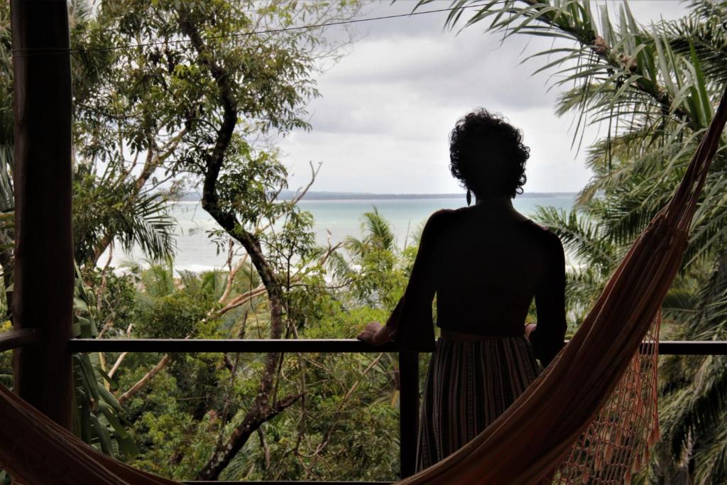 a woman in a hammock looking out at the ocean at Casa Mestiça in Ilha de Boipeba