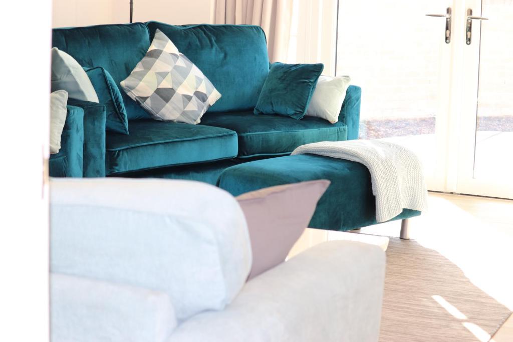 uma sala de estar com um sofá azul com almofadas em Eve's Corner em Bideford