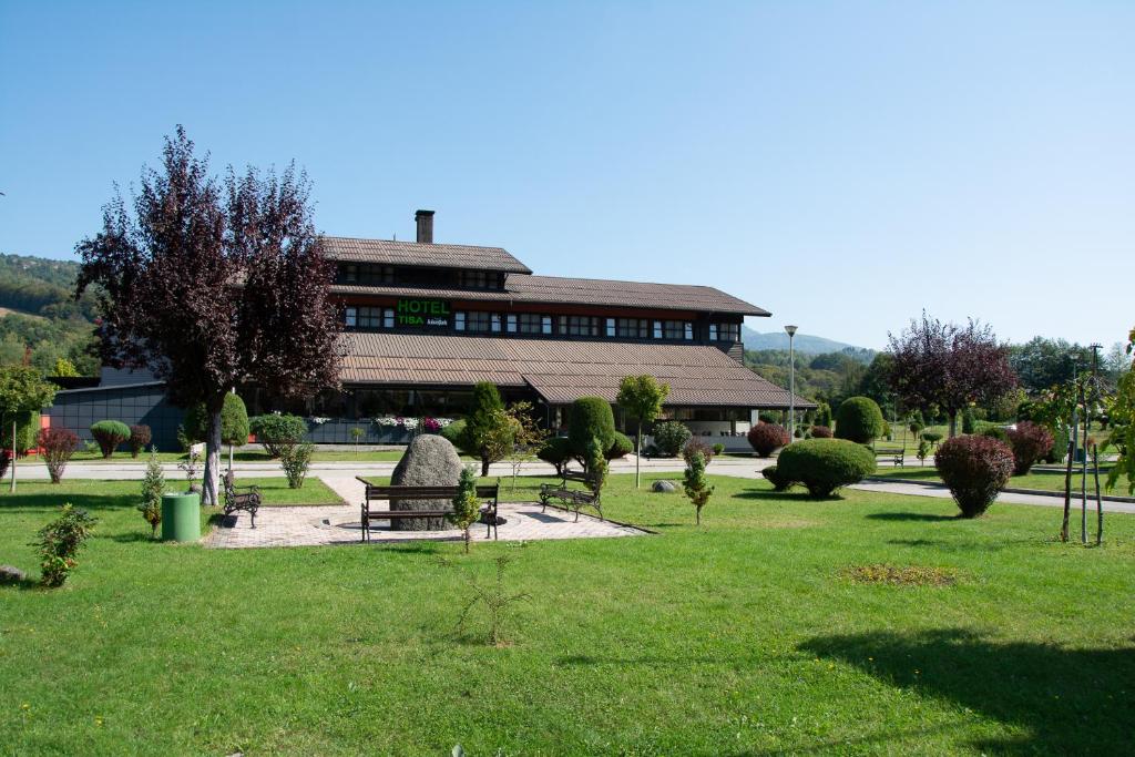 Hotel TISA في Busovača: مبنى به حديقة مع مقعد على العشب