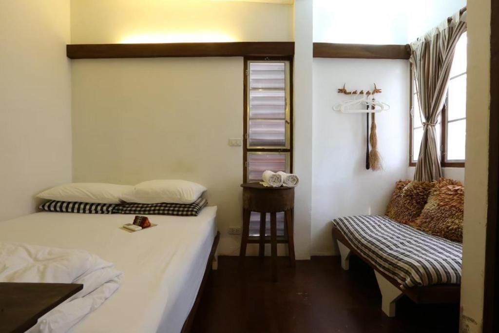 a room with two beds and a chair in it at Baan Rare Guesthouse in Udon Thani