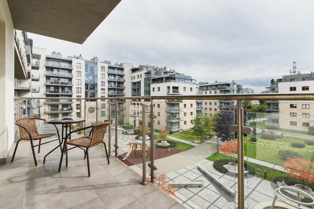 a balcony with a table and chairs and a view of a city at Apartments Kraków Wiślane Tarasy by Renters in Krakow