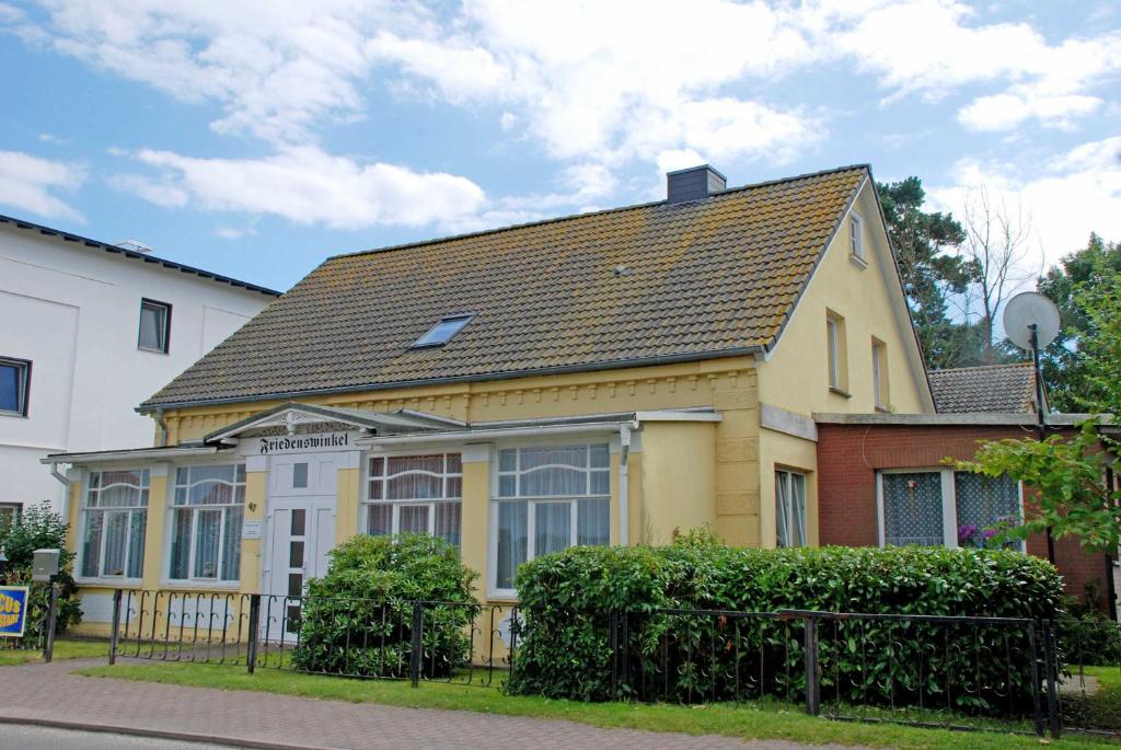 a yellow house with a brown roof at Haus Friedenswinkel in Thiessow