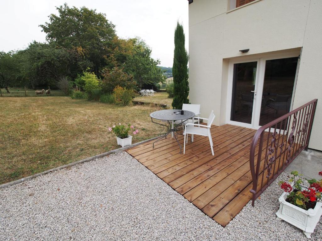 a wooden deck with a table and chairs on a yard at Escale en Revermont in Saint-Lothain