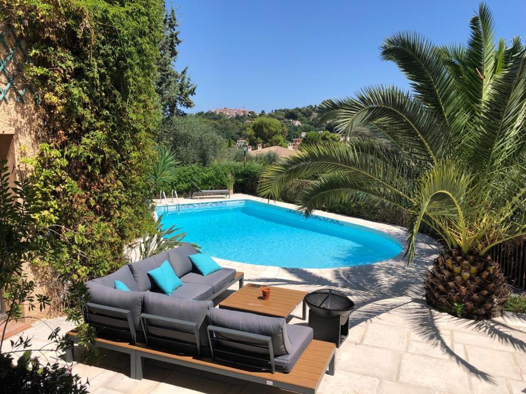 a pool with a couch and a table next to it at Les Cypres in Mougins