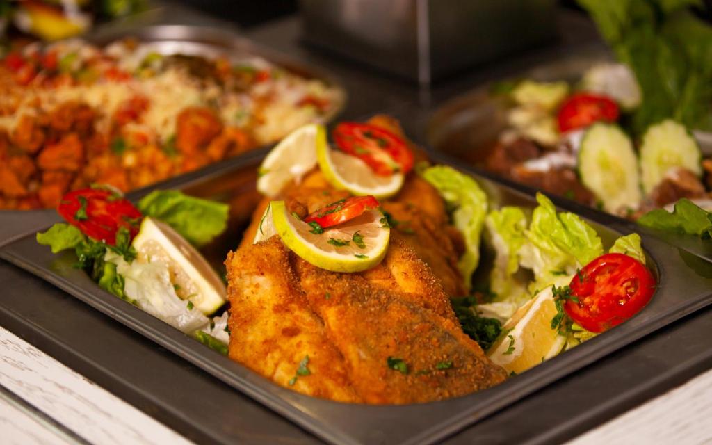 a tray of food with chicken and salad and pizza at Hotel Nour Congress & Resort in Bizerte