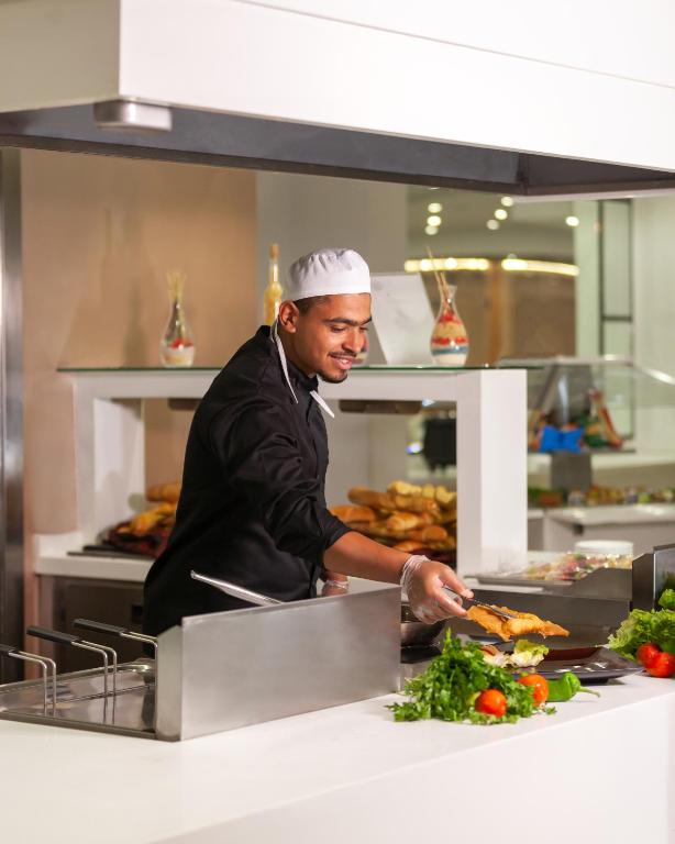 a chef preparing food in a restaurant kitchen at Hotel Nour Congress & Resort in Bizerte