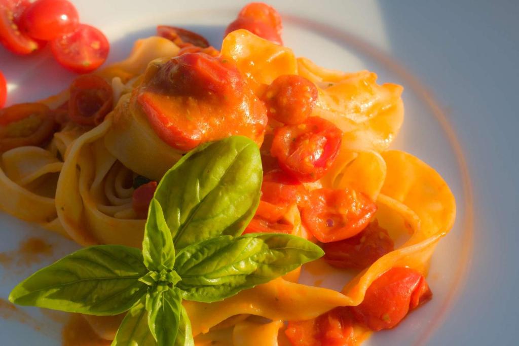 a plate of pasta with tomatoes and basil on it at Hotel La Corte Del Sole in Noto