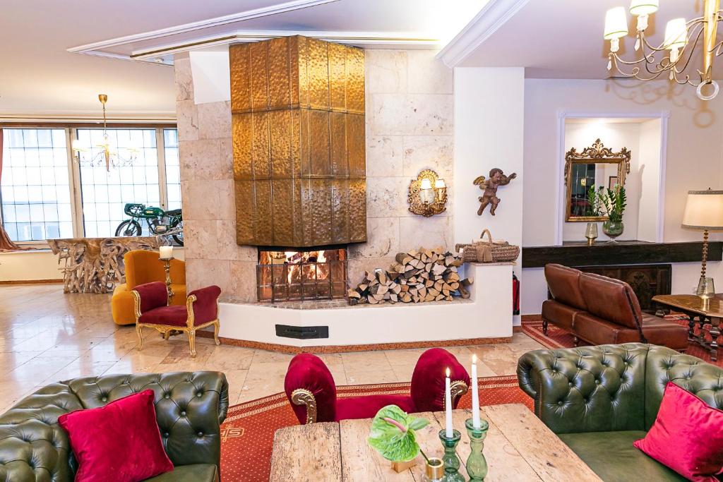 a living room with a fireplace and leather furniture at Sporthotel Igls in Innsbruck
