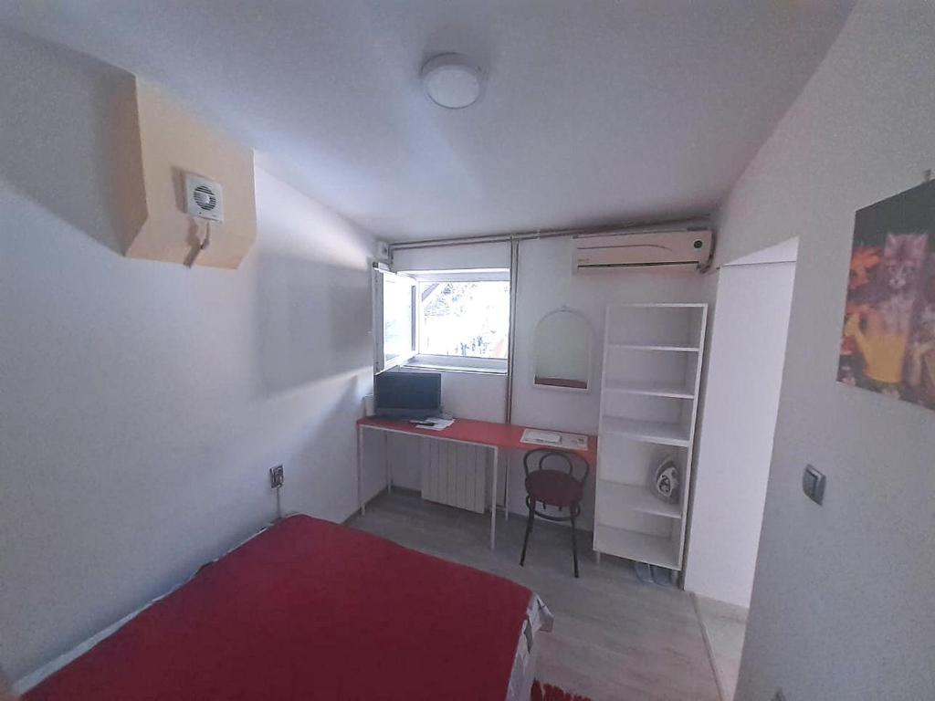 ベオグラードにあるStudio Krunska 6のデスク、ベッド、窓が備わる小さな客室です。