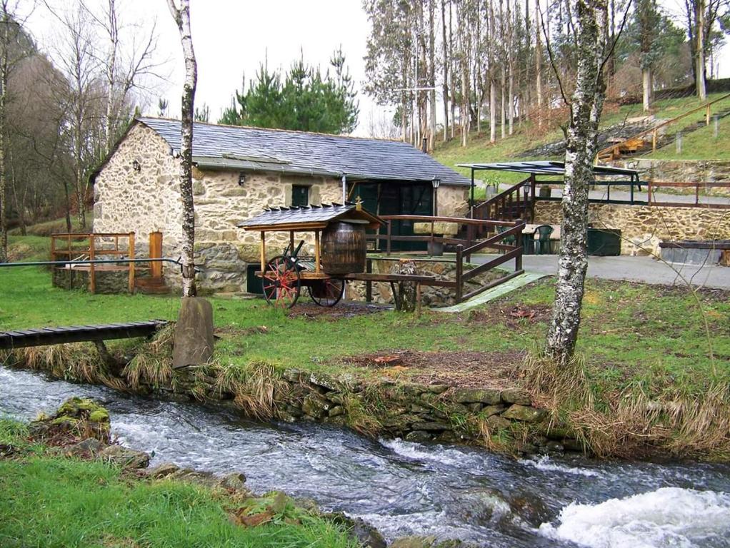una cabaña de madera con un río delante en Molino de Louzao, en Palas de Rei 