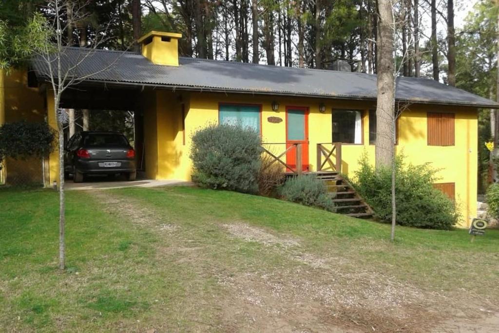 a yellow house with a car parked in front of it at Casa completa en el bosque para 8 personas no aceptamos grupos de jovenes in Pinamar