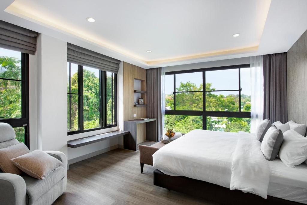 a bedroom with a bed and a couch and windows at Reiz - Private Residence in Chiang Mai