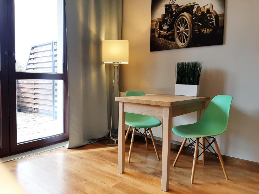 een eettafel met twee groene stoelen en een lamp bij Apartamenty Lubin - Kamieniczka w Centrum in Lubin
