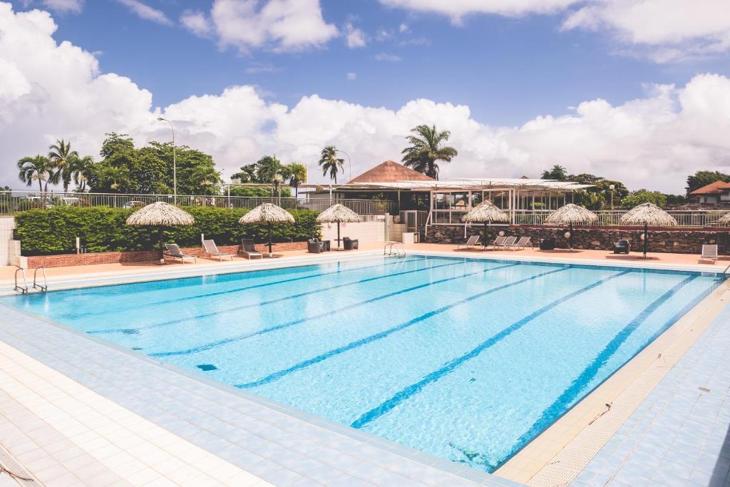 a large swimming pool with chairs and a building at Hotel des Roches in Kourou
