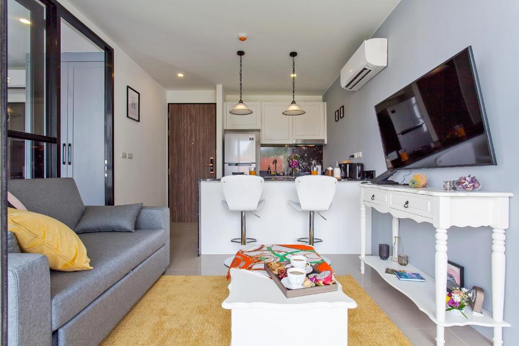 a living room with a couch and a kitchen at Palmyrah Surin Apartments by Beringela in Surin Beach