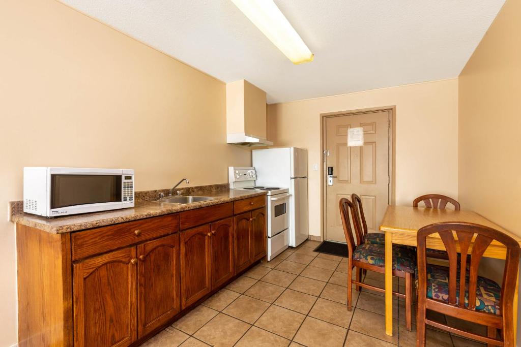 a kitchen with a sink and a table with a microwave at Ramada by Wyndham Coquitlam in Coquitlam
