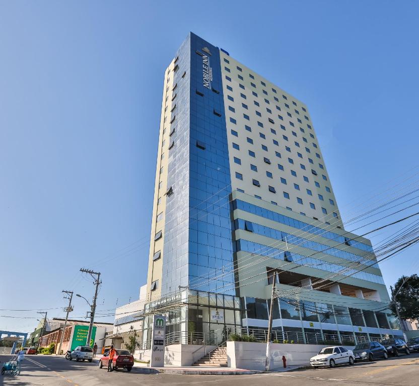 een hoog blauw gebouw met auto's geparkeerd voor het bij Nobile Inn Meridional Cariacica in Cariacica