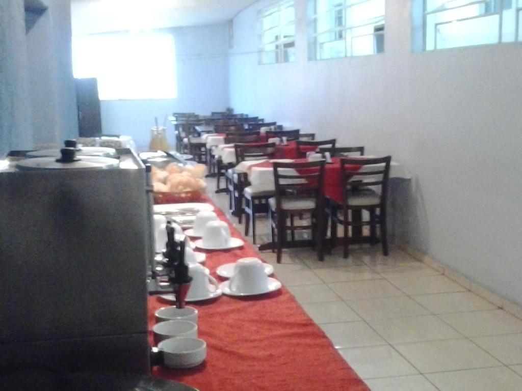 uma sala de jantar com uma mesa longa com pratos e chávenas em Alfa Hotel Vespasiano em Vespasiano