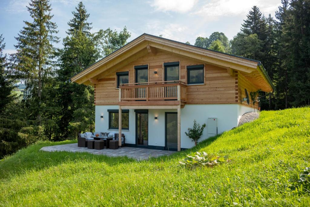 dom na szczycie trawiastego wzgórza w obiekcie Chalet Alpenherz w mieście Kirchberg in Tirol