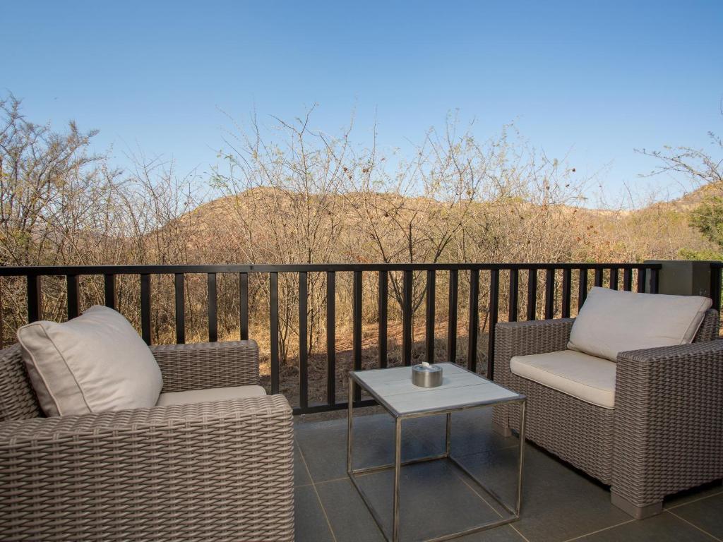 two wicker chairs and a table on a balcony at Shepherds Tree Game Reserve in Pilanesberg
