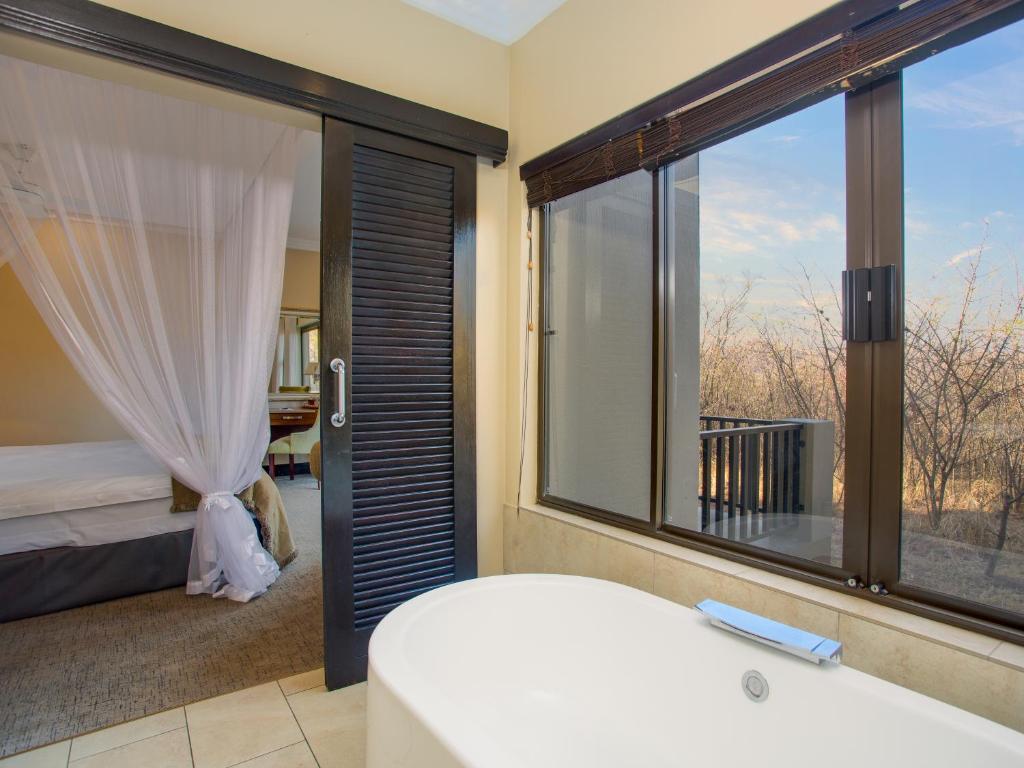a bedroom with a bed and a large window at Shepherds Tree Game Reserve in Pilanesberg