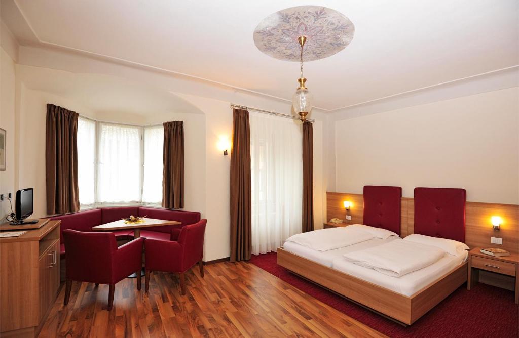 Habitación de hotel con cama, mesa y sillas en Hotel Andreas Hofer, en Egna