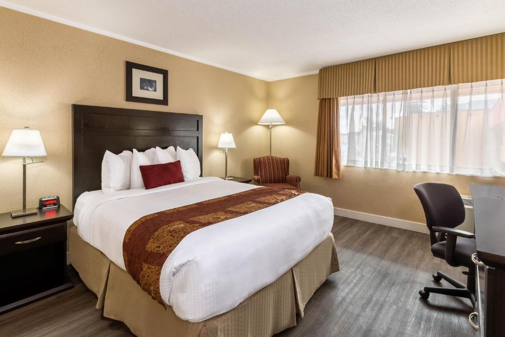 a hotel room with a large bed and a desk at Ramada by Wyndham Coquitlam in Coquitlam