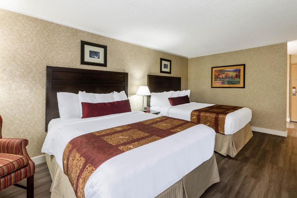 a hotel room with two beds and a chair at Ramada by Wyndham Coquitlam in Coquitlam