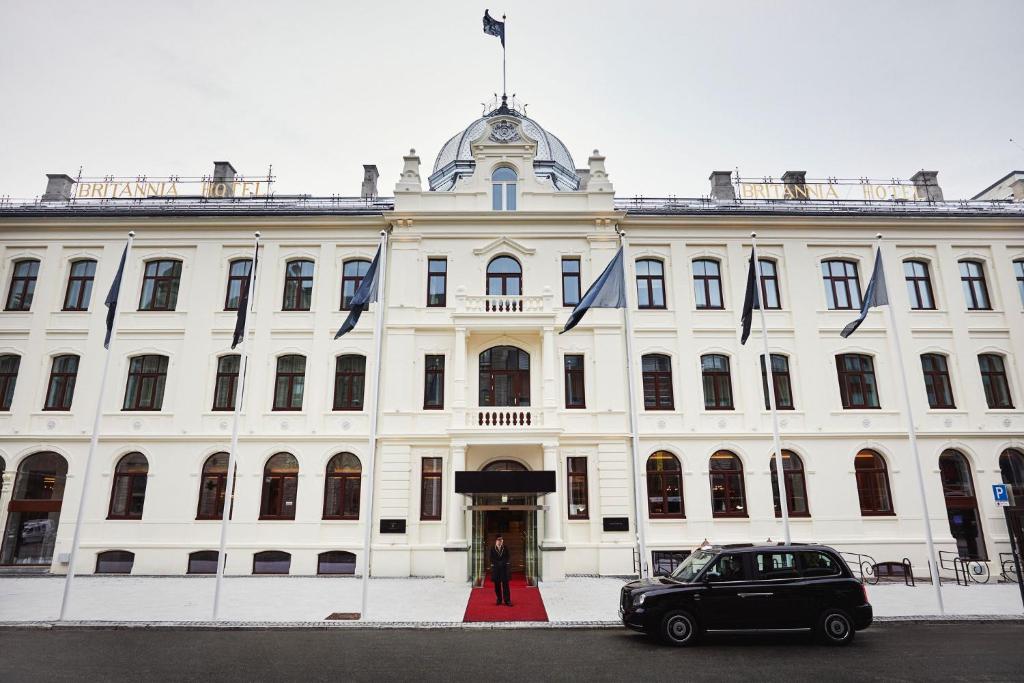 um carro estacionado em frente a um grande edifício branco em Britannia Hotel em Trondheim