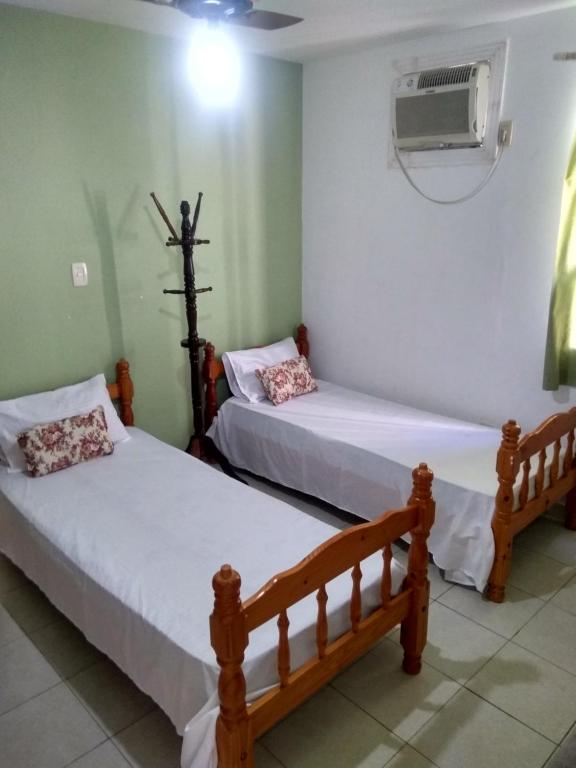 a bedroom with two beds and a air conditioner at Apto Praia da Enseada 4 pessoas in Guarujá