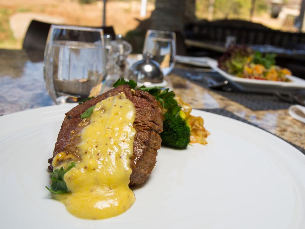 a white plate with a steak and broccoli on a table at Shepherds Tree Game Reserve in Pilanesberg