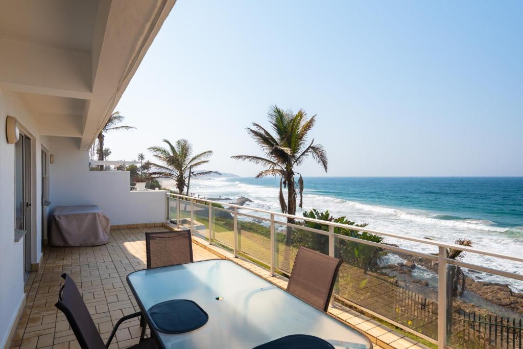 a balcony with a table and chairs and the ocean at Pebble Beach 13 in Ballito