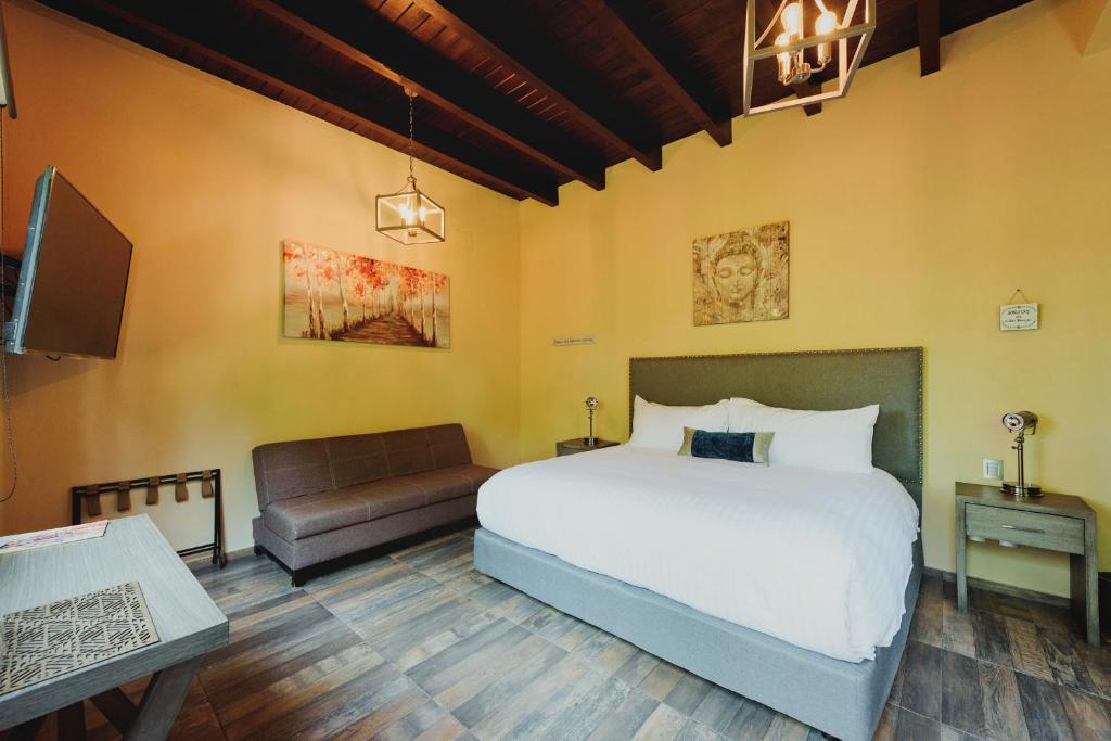 1 dormitorio con cama, sofá y TV en Loto Azul Hotel & Spa, en Valle de Bravo