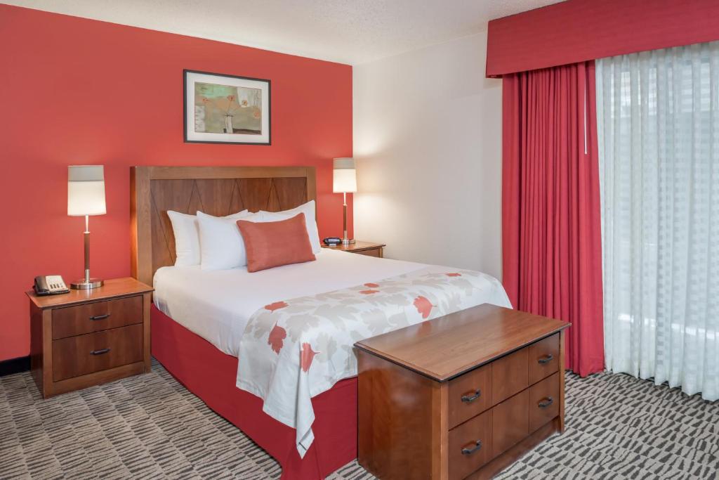 una camera d'albergo con letto e parete rossa di Craigshire Suites St Louis Westport Plaza a Maryland Heights