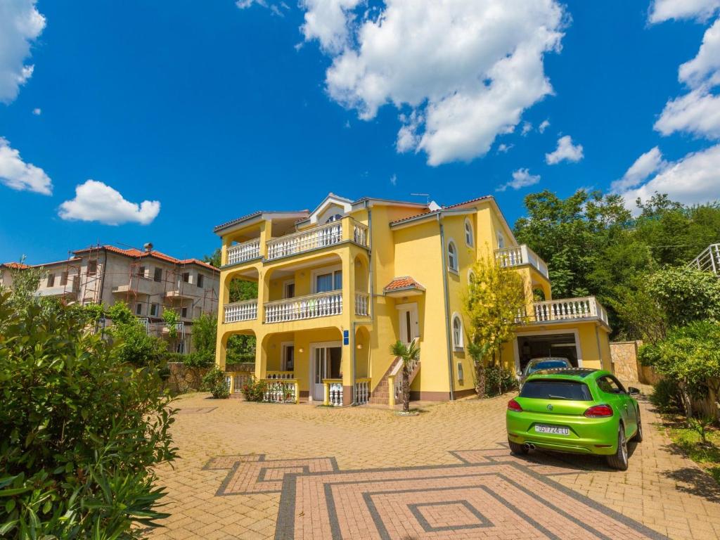 a yellow house with a car parked in front of it at Apartments Artan in Crikvenica