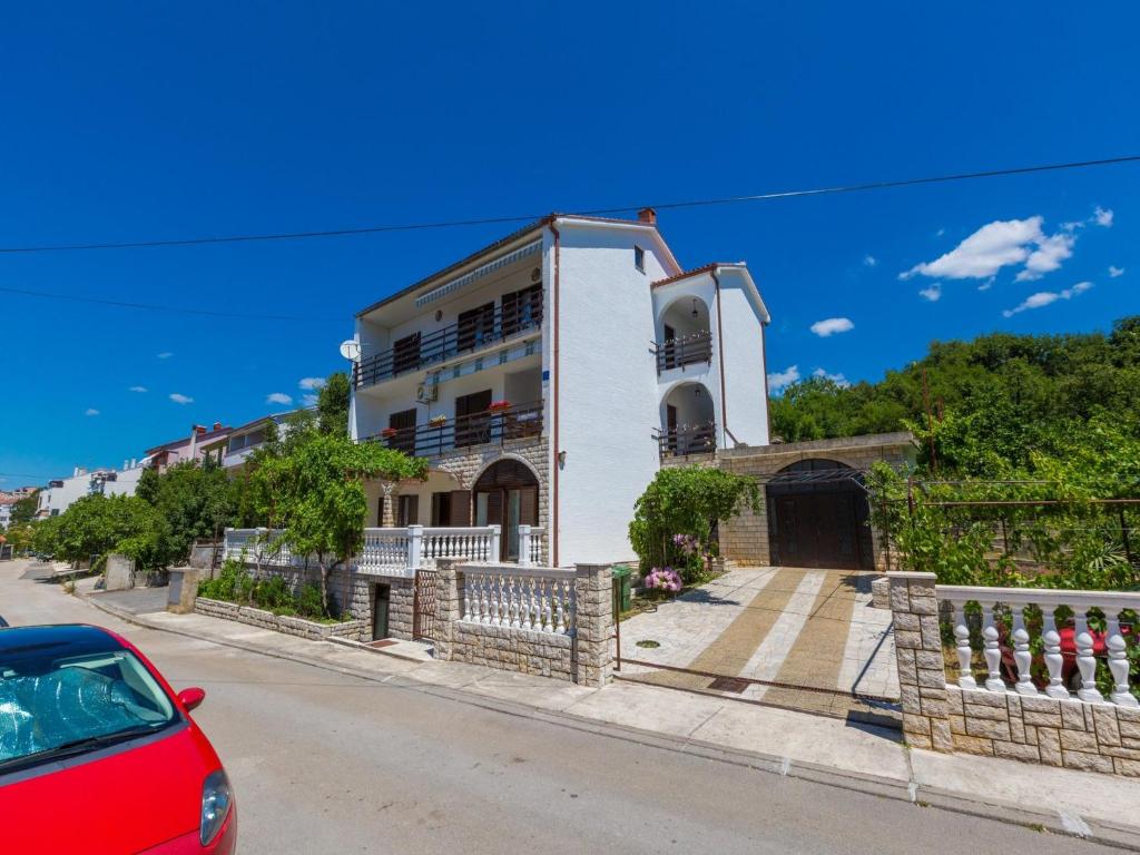 una casa en una calle con un coche rojo aparcado delante en Apartments Ankica, en Crikvenica